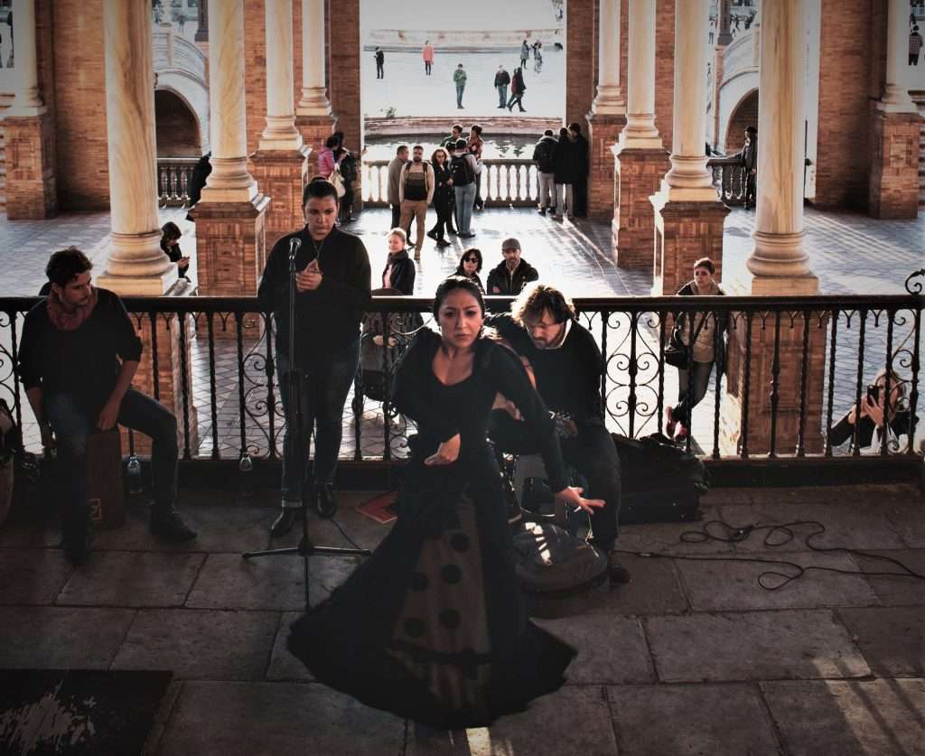 Small band is playing easy to play flamenco songs for guitar, woman is dancing