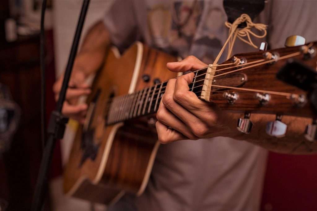 Guitarist plays steel-string acoustic guitar